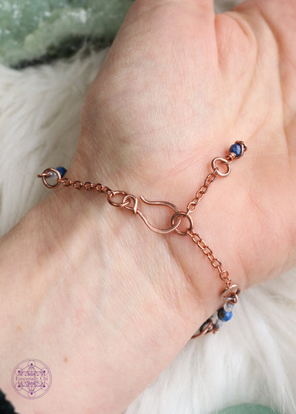 Copper wire wrapped bracelet features Lapis Lazuli beads. Showing the backside of bracelet on wrist to see hook clasp and beaded extension chain and Lapis Lazuli charm that you can hold onto to secure the clasp.