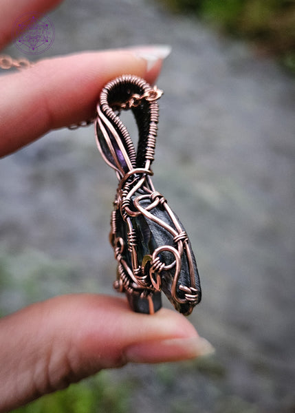 Abalone and Amethyst mermaid tail pendant wrapped in copper wire filagree design. The fin is an Abalone moon and the amethyst is faceted like the scales on the mermaid tail. Showing the curls of the wire along the right side.