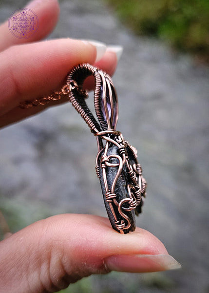 Abalone and Amethyst mermaid tail pendant wrapped in copper wire filagree design. The fin is an Abalone moon and the amethyst is faceted like the scales on the mermaid tail. Showing the curls of the wire along the left side.