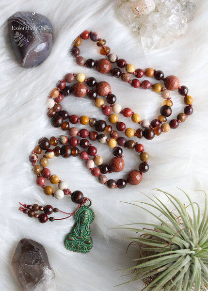 Experience divine energy with our Mookaite Crystal Beaded Mala featuring a Kwan Yin bronze pendant. Mookaite, goldstone, garnet, smoky quartz, and wood beads, meticulously crafted for those who are on a healing journey. 30" long, shorter than traditional Malas, ensuring both style and ease of wear.