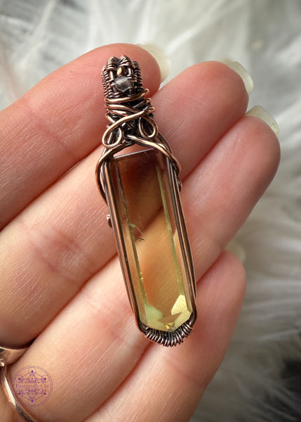 Copper wire wrapped Natural Citrine point pendant with a small smoky quartz bead in the bail. Held in hand to show size reference with a white faux fur background to show the details inside the crystal. There are two phantoms at the top of the crystal and the wrap doesn't cover any of the crystal to allow light to shine through the back.