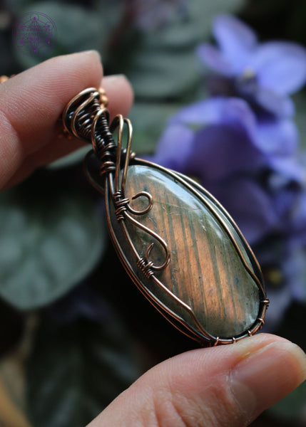 Orange Labradorite is a powerful stone of creativity, transformation, and emotional healing. It resonates with the Sacral and Solar Plexus Chakras, supporting emotional balance, creative expression, and personal empowerment. Oval cabochon shaped crystal with two swirls of copper coming over the left face and a simple design to show the bright orange flash.