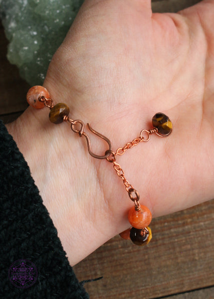 Copper wire wrapped bracelet features 8mm Orchid Calcite beads individually wrapped with faceted rondelle Tiger Eye beads individually wrapped, linking together for an elegant bracelet. Shown worn with the clasp on the backside of the bracelet, featuring a tiger eye charm hanging from the extension chain.