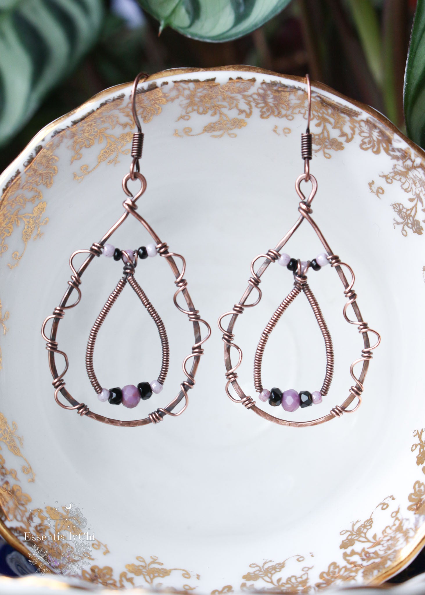 A pair of elegant tear-drop-shaped earrings with intricate filigree designs along the edges. These eye-catching earrings feature an additional tear-drop dangle inside, adorned with delicate pink and black seed beads. At the center of each earring, a faceted Phosphosiderite bead adds a touch of sophistication and metaphysical charm. The combination of filigree detailing, seed beads, and the unique gemstone creates a stylish and distinctive accessory, perfect for adding a touch of elegance to any outfit.