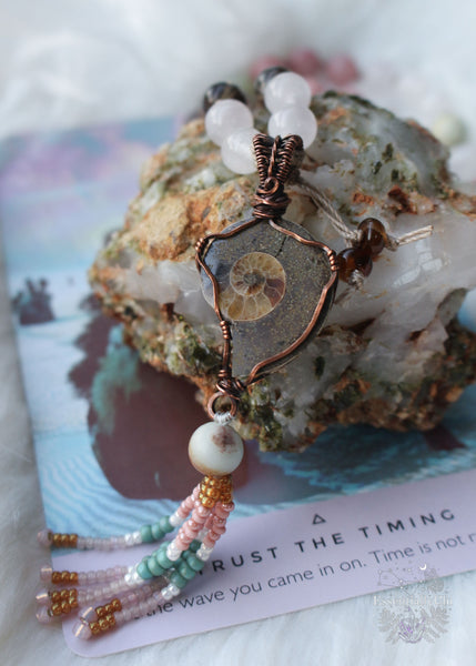 This mala is 72 beads that slip easily over the head and short enough where the pendant sits around the heart space. The pendant is a copper wire wrapped ammonite with a beaded beaded tassel. Mala beads include rose quartz for self love, smoky quartz for protection and positivity, pink sandstone for helping you stand strong in the midst of change, and amazonite for comfort in transition. Ammonite helps with stability in the midst of trauma.