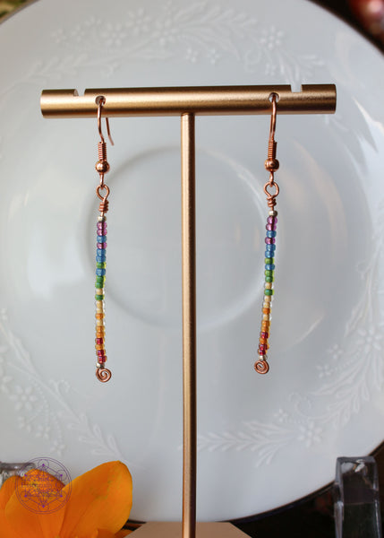 Pride Rainbow Earrings with seed bead drop design in rainbow pattern of Purple to Red on copper wire hanging 2.25" from rose gold-toned ear wires.