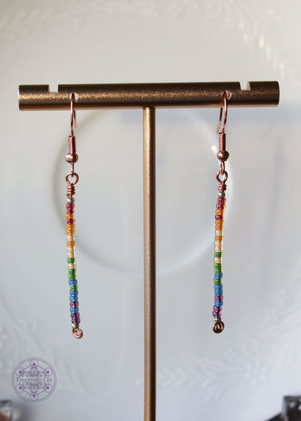 Pride Rainbow Earrings with seed bead drop design in rainbow pattern of red to purple on copper wire hanging 2.25" from rose gold-toned ear wires.