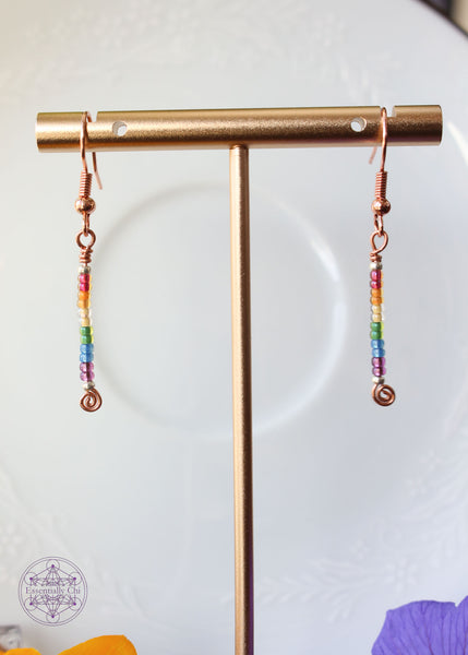 Pride Rainbow Earrings with seed bead drop design in rainbow pattern of red to purple on copper wire hanging 1.75" from rose gold-toned ear wires.