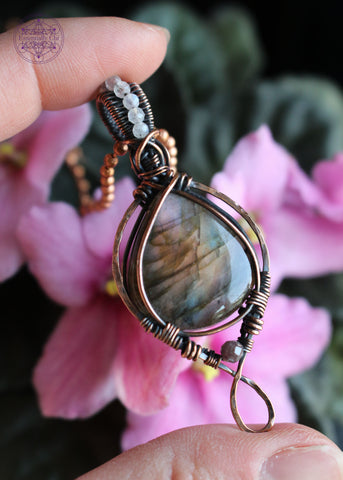 purple, orange, and blue green flash labradorite in a teardrop shape with a simple bail and 2mm moonstone faceted beads along the center of the bail. the bottom has a 3mm watermelon tourmaline attached as an accent stone.