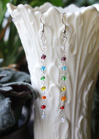 Rainbow Beaded Opal Dangle Earrings featuring glass rainbow-colored beads and a genuine Ethiopian opal at the base. These 3.5-inch earrings are suspended from stainless steel ear hooks, offering a vibrant and stylish celebration of color therapy