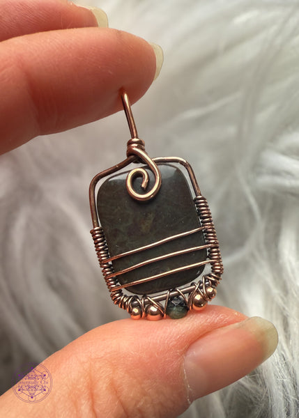 Swirl pendant variation is a dark green stone with accent beads of copper and dark green tourmaline along the base and three lines of copper along the bottom half of the pendant for security and design. 