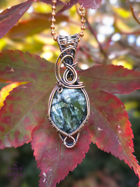 feathery green oval seraphinite crystal wrapped in copper wire for an elegant everyday necklace. There is a small loop at the bottom to hug around the bottom of the crystal and a few swirls along the bail. Hung on a copper ball and chain necklace.