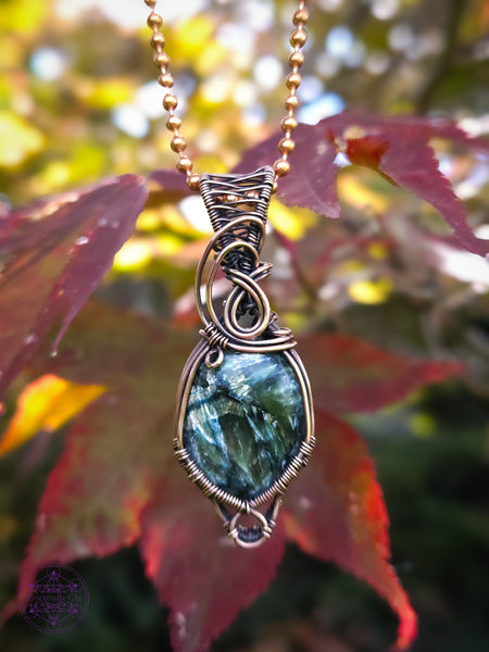 feathery green oval seraphinite crystal wrapped in copper wire for an elegant everyday necklace. There is a small loop at the bottom to hug around the bottom of the crystal and a few swirls along the bail. Hung on a copper ball and chain necklace.