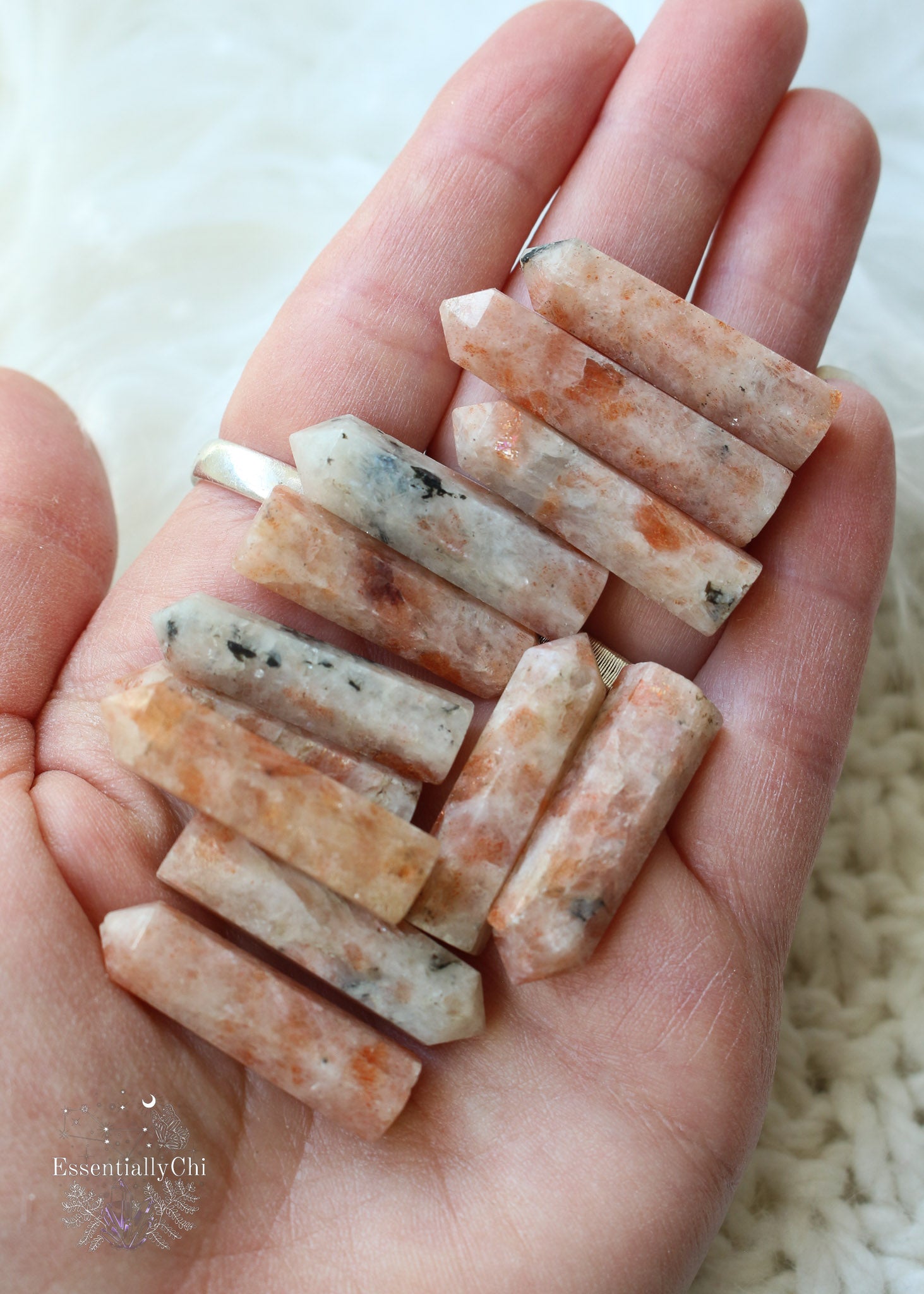Mini sunstone points about 1" length in hand with variations of light orange with bright orange flash and black spots.