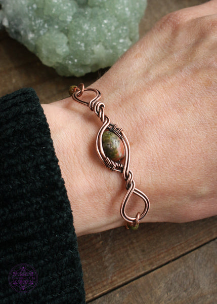 Copper wire wrapped bracelet features an oval Unakite bead wrapped in twisted copper with loops on each end. Shown on wrist to see how it lays. 