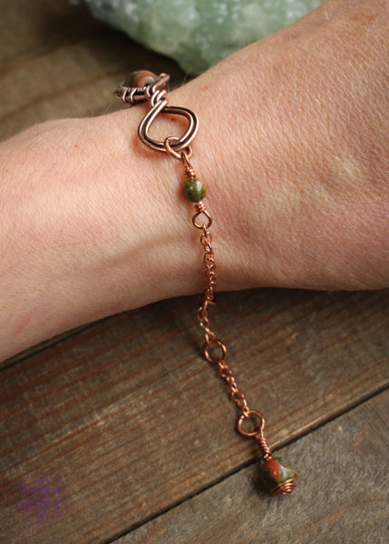 Twisted copper wire wrapped bracelet features Unakite beads. Showing the side of bracelet on wrist to see the small unakite bead extension and the charm at the end of the bracelet. 