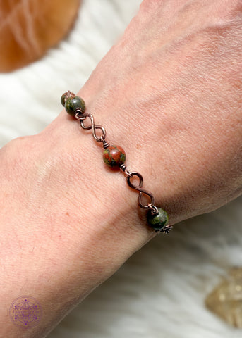 Copper wire wrapped bracelet features 6mm Unakite beads individually wrapped with figure 8 Infinity links in-between for an elegant bracelet. Shown on wrist to see how it lays. 