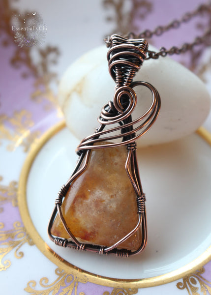 Nebu Orange Aventurine Copper Wire Wrapped Necklace - A captivating triangle-shaped pendant inspired by ancient Egyptian motifs, featuring a three-swoop bail design. The orange aventurine sparkles with golden hues, reminiscent of a radiant sunset. This handcrafted necklace, 2 inches in length, hangs gracefully from a 20-inch copper chain, symbolizing creativity, confidence, and the warm embrace of celestial energies.